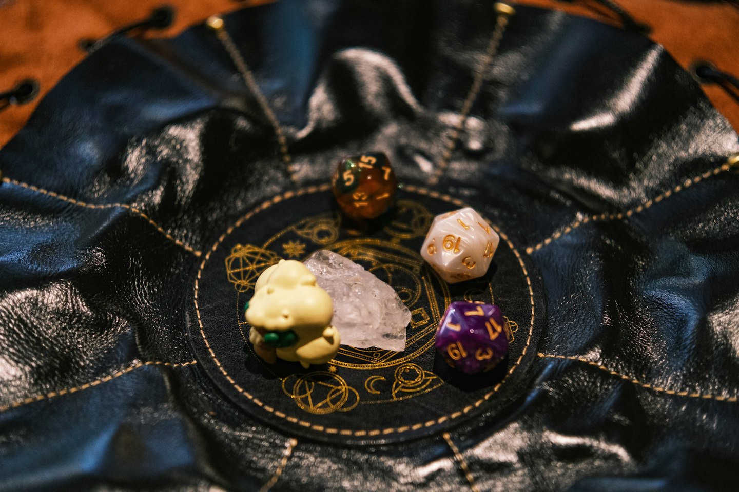 Tabletop gaming dice and a figurine sit on a leather pouch.