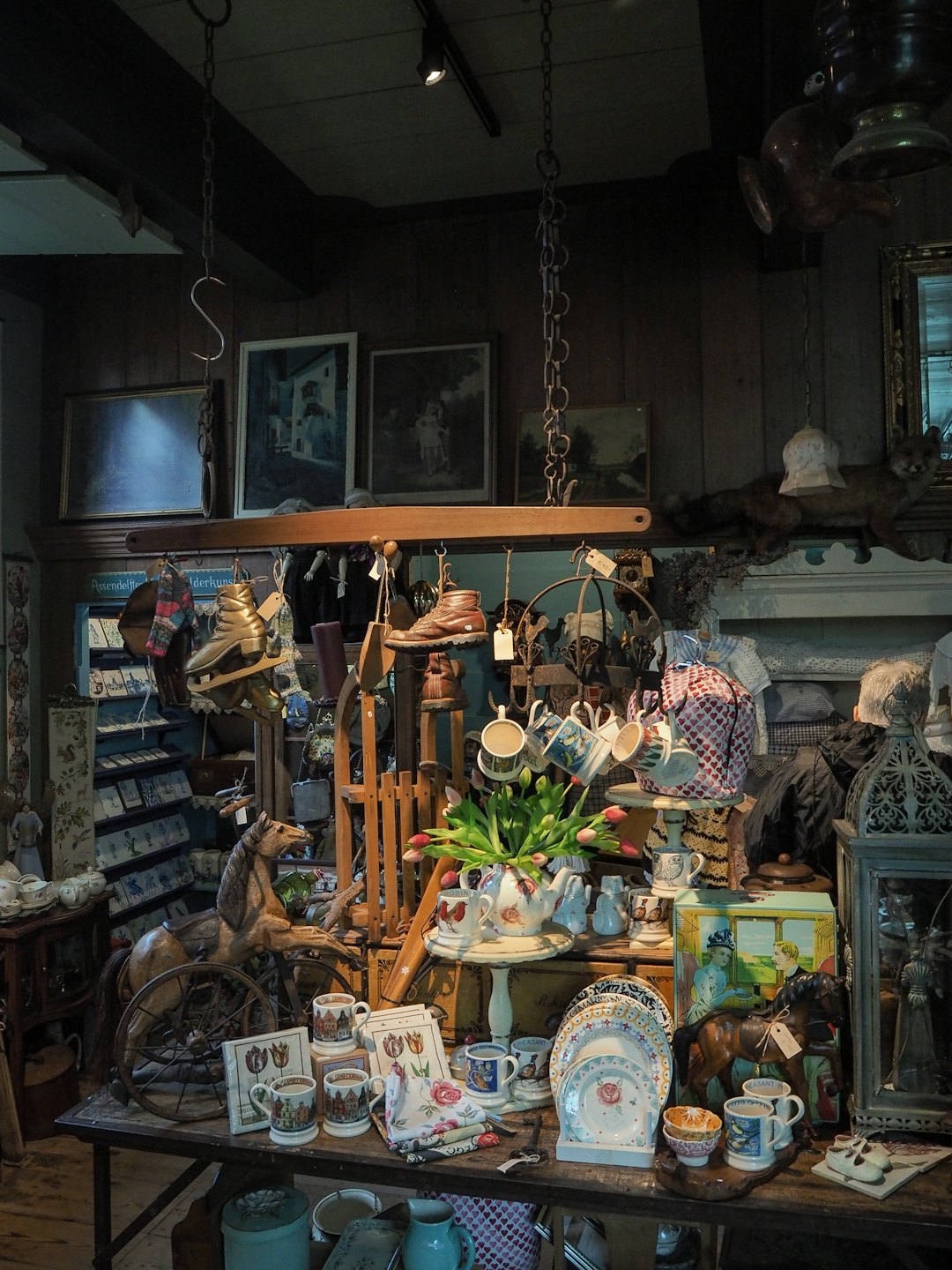 Antique shop table filled with ceramics and a wooden horse.