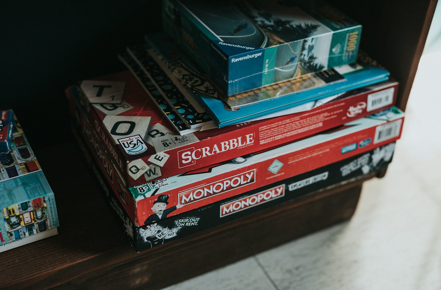 Stack of board games and puzzles on a wooden shelf.