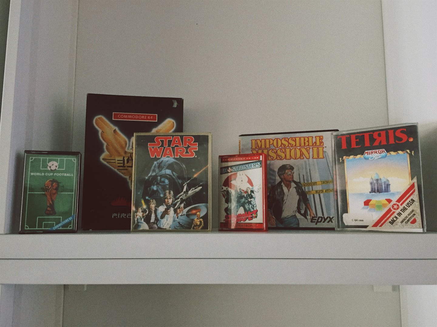 Vintage video game boxes arranged neatly on a white shelf.