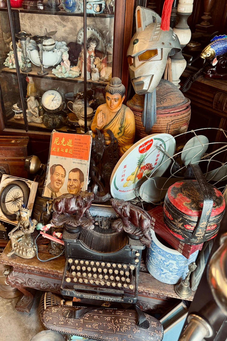 A wooden table laden with eclectic vintage items and a display cabinet.