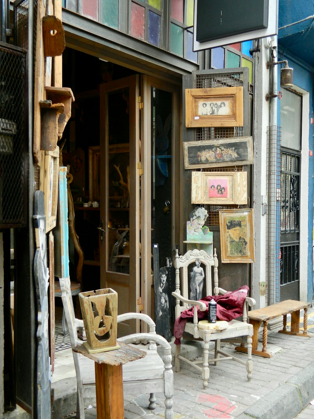 Eclectic vintage shop exterior displaying wooden furniture and framed artwork.