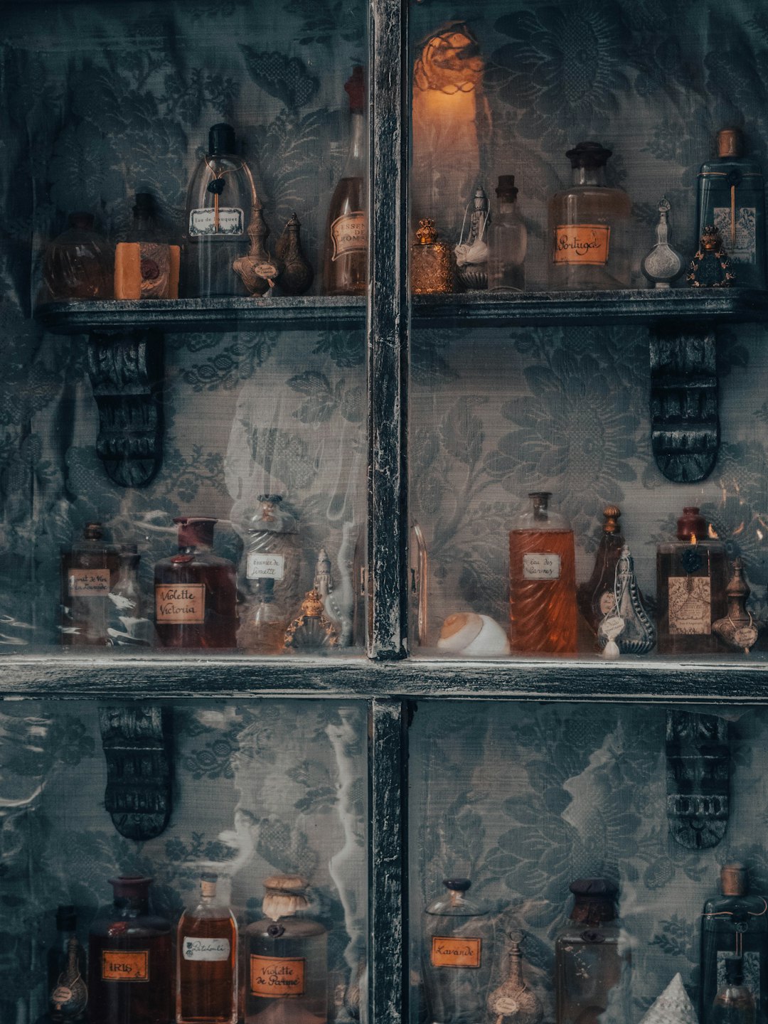 Vintage glass bottles and decorative items in an antique display cabinet.
