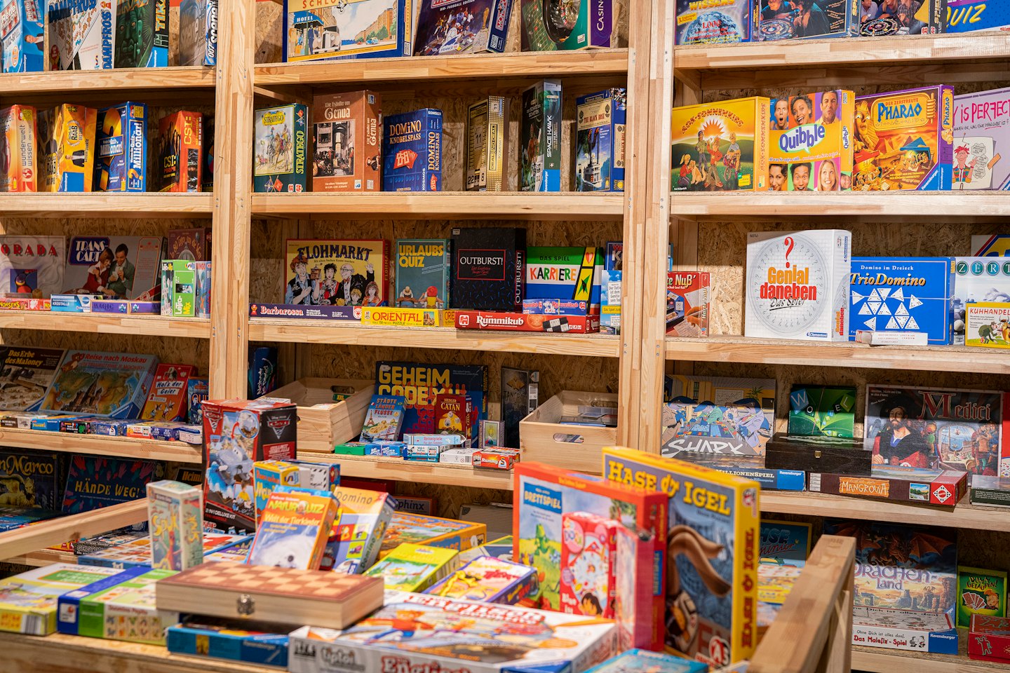 Colorful board games and puzzles displayed on wooden shelves.