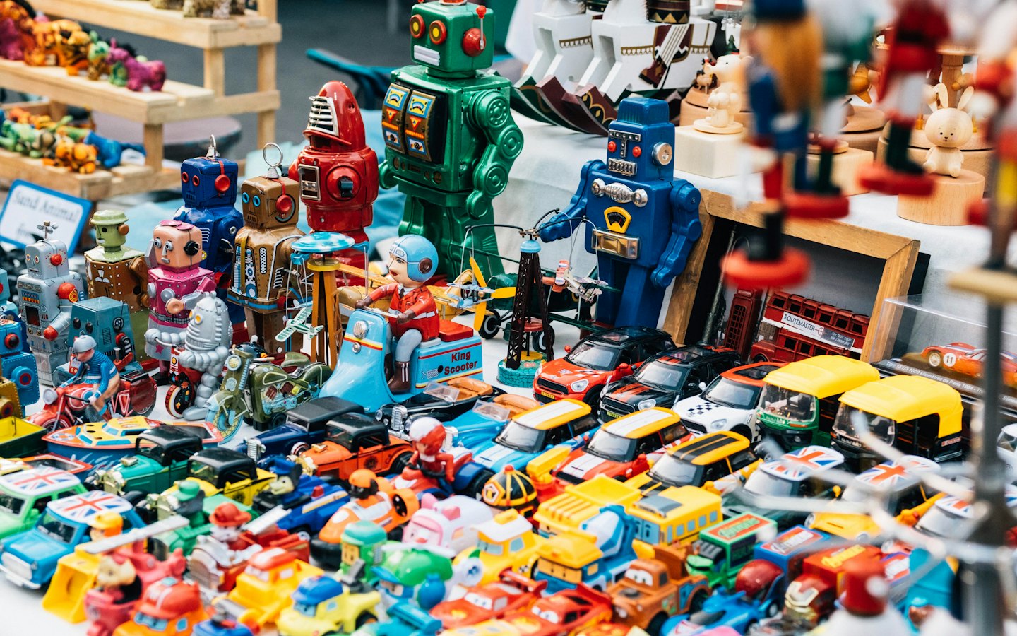 Assorted vintage robots and die-cast cars on a market stall.