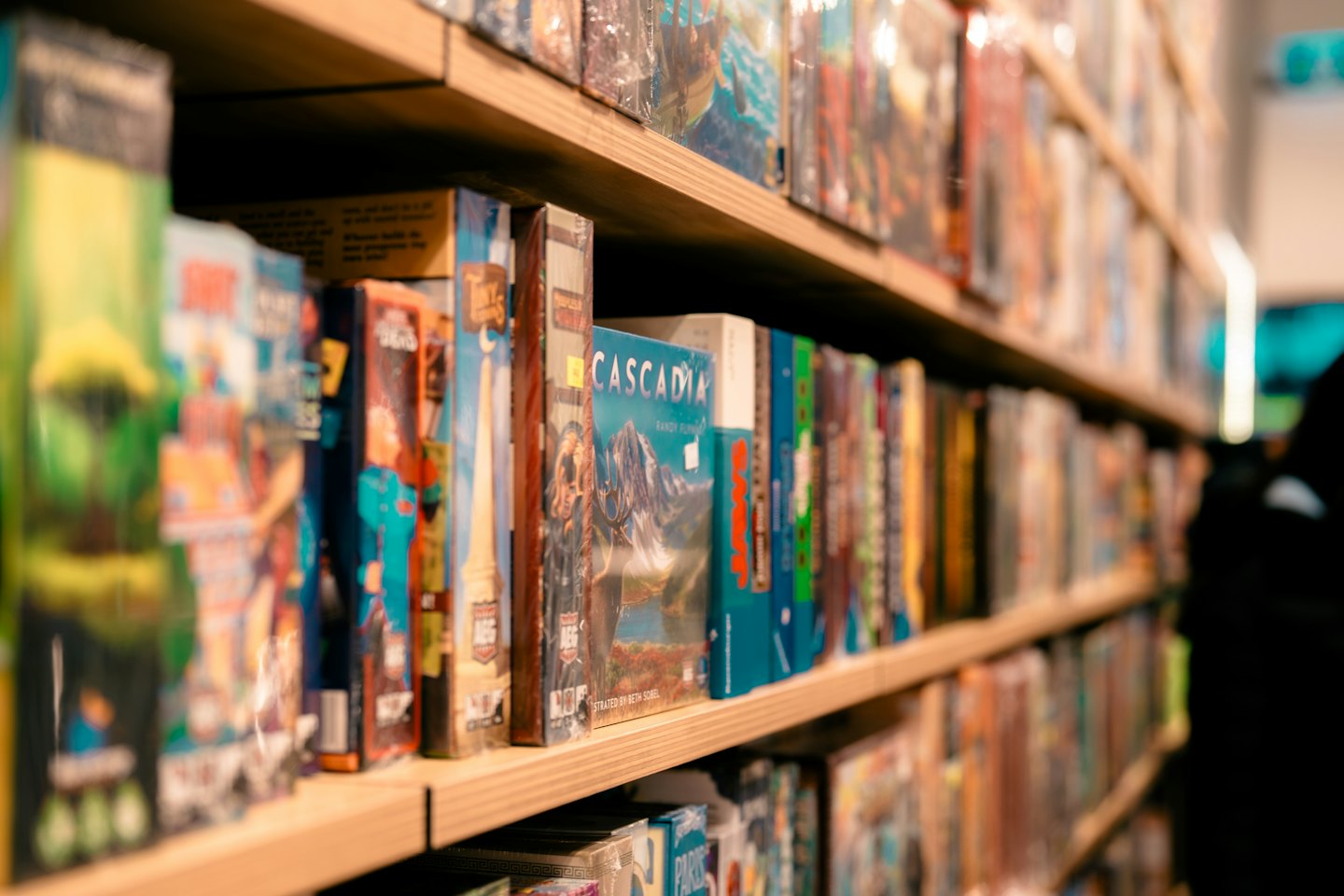 Colorful board game boxes stacked neatly on wooden retail shelves.